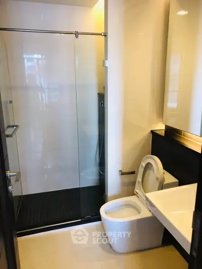 Modern bathroom with glass shower and sleek fixtures in contemporary apartment.