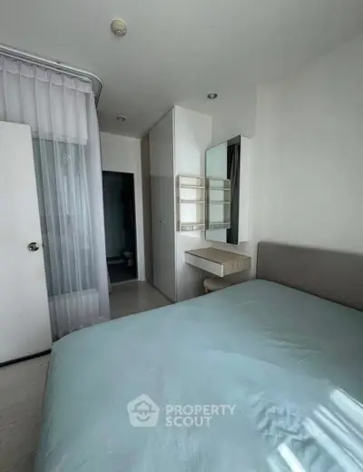 Cozy bedroom with modern decor and natural light, featuring a comfortable bed and stylish vanity area.