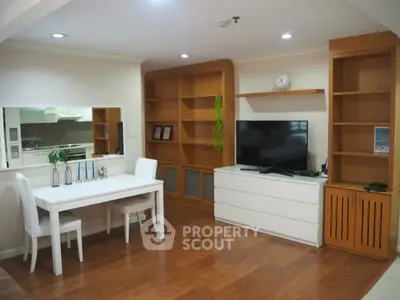 Modern living room with wooden flooring, white furniture, and built-in shelving.