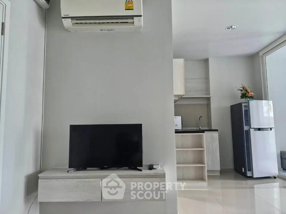 Modern living room with sleek TV setup and compact kitchen area, perfect for urban living.