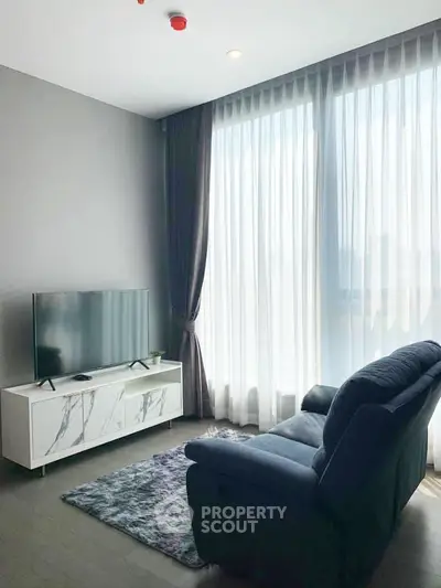 Modern living room with large window, cozy sofa, and sleek TV stand in a bright apartment.