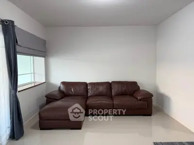 Spacious living room with elegant brown leather sofa and large window, perfect for relaxation.
