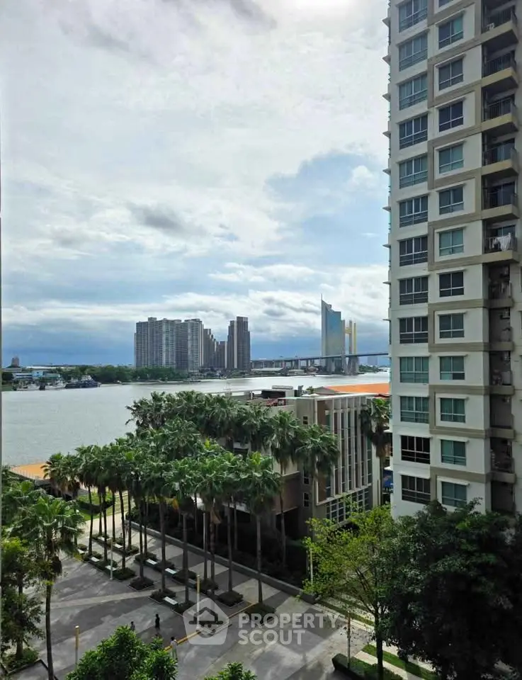 Stunning riverfront view from high-rise building with lush greenery and modern architecture.