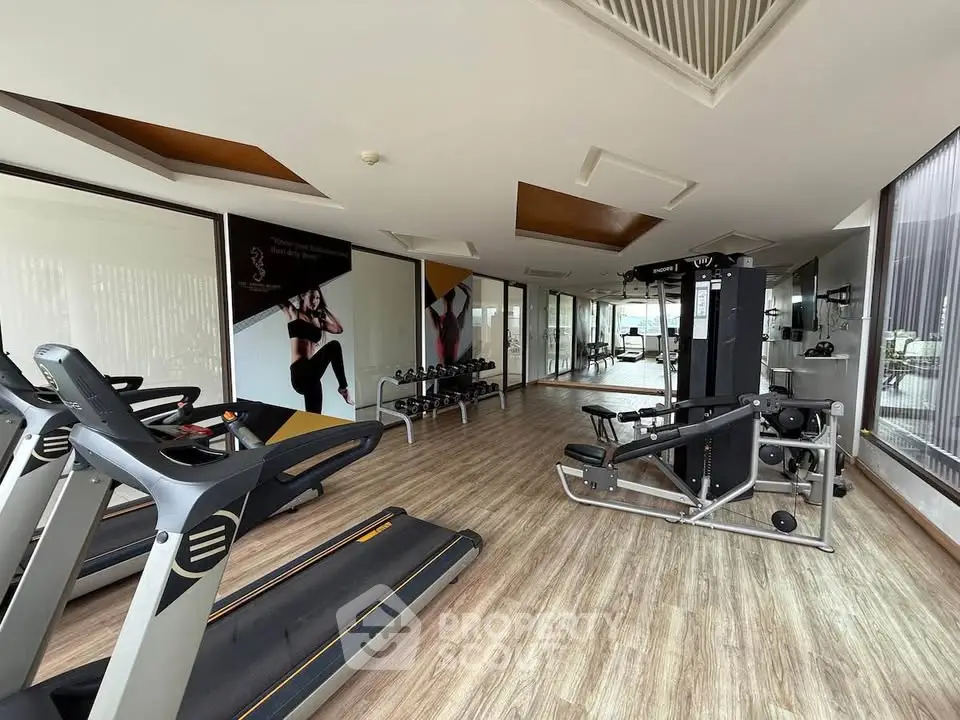 Modern gym with state-of-the-art equipment and wooden flooring in a luxury residential building.