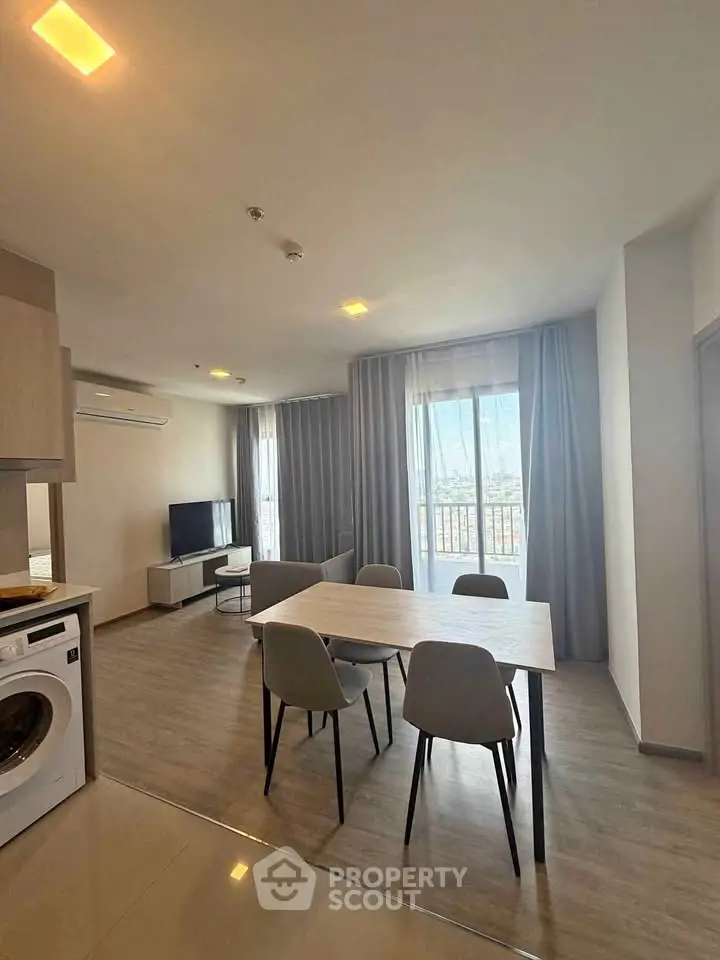 Modern living room with dining area and washing machine, featuring large windows and stylish decor.