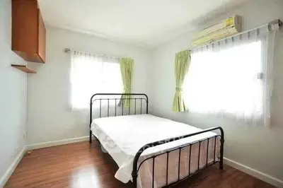 Bright bedroom with metal bed frame, wooden floor, and air conditioning.