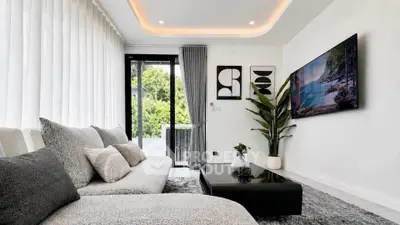 Modern living room with sleek decor and large TV, featuring a cozy sofa and lush greenery view.