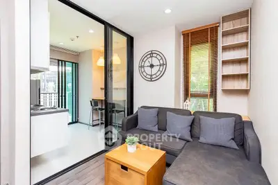 Modern living room with cozy sofa and stylish decor adjacent to open kitchen area.