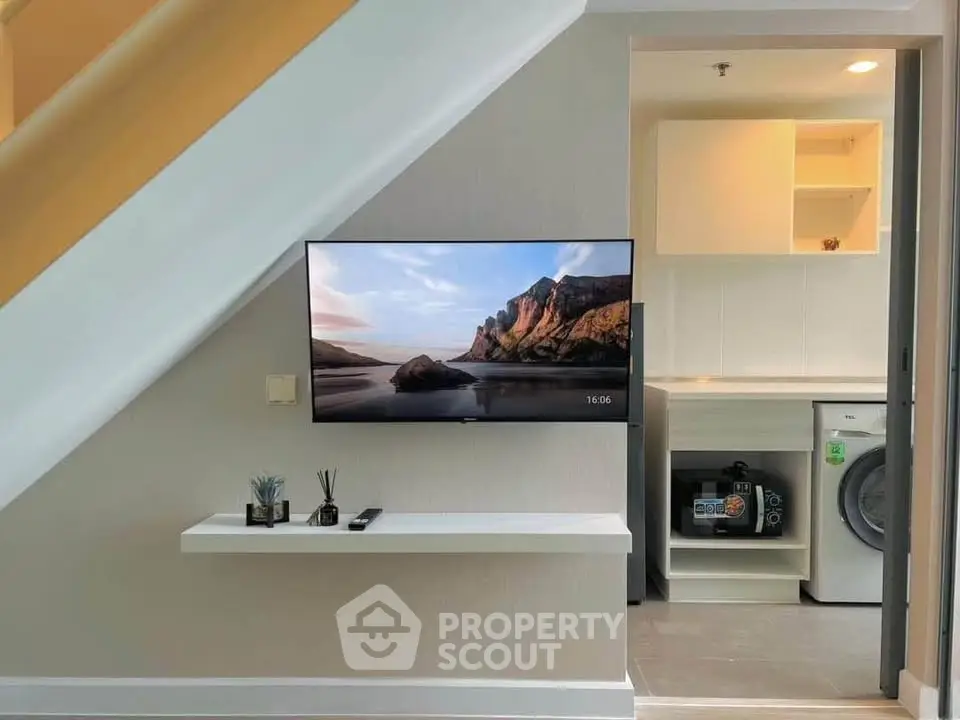 Modern living space with wall-mounted TV and compact laundry area
