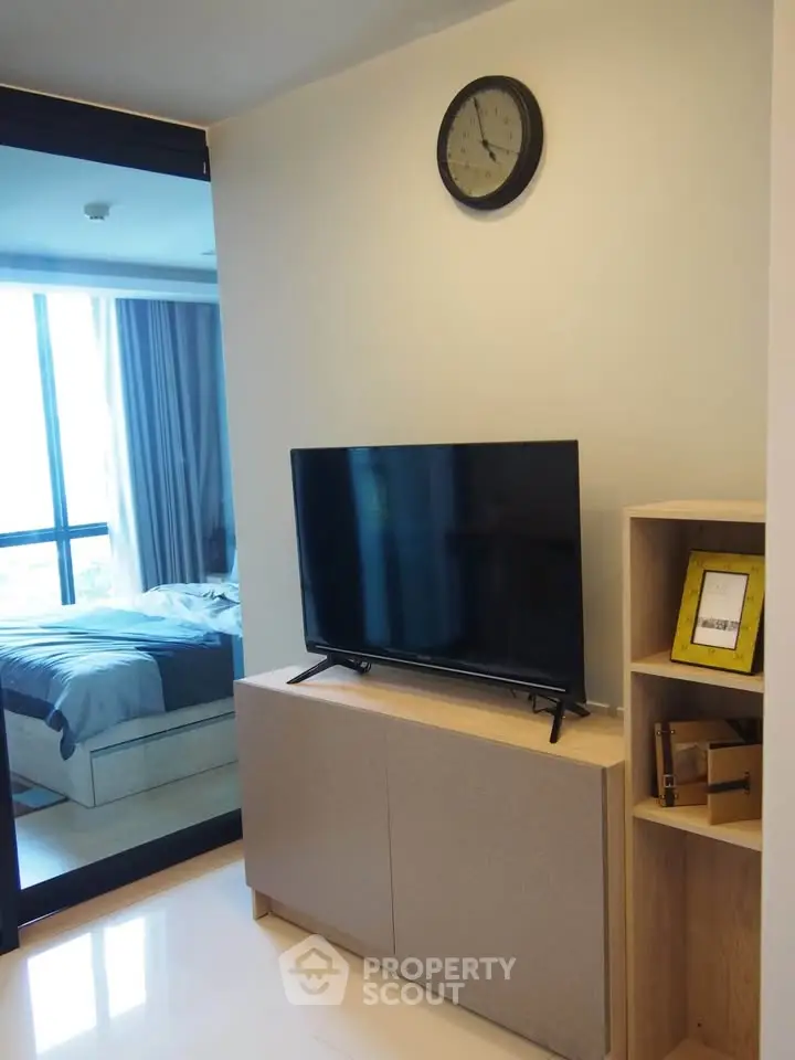 Modern apartment interior with TV and bedroom view, sleek design and natural light.