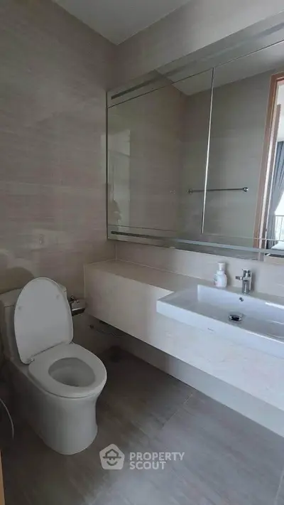 Modern bathroom with sleek fixtures and large mirror in a contemporary home.