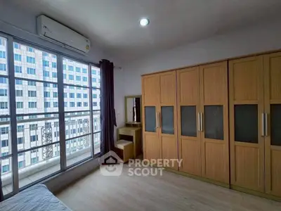 Spacious bedroom with large windows and built-in wardrobes in modern apartment.
