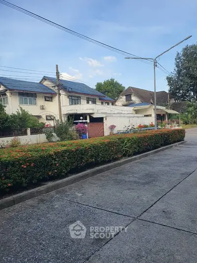 Charming suburban street with lush greenery and cozy homes under a clear blue sky.