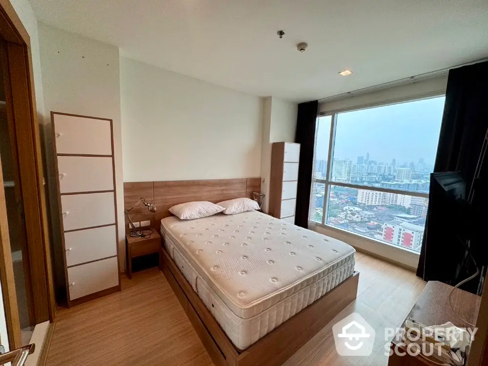 Modern bedroom with city view, featuring a comfortable bed and sleek wooden furniture.