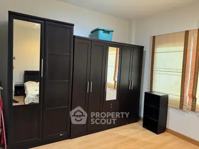 Spacious bedroom with elegant dark wood wardrobes and natural light