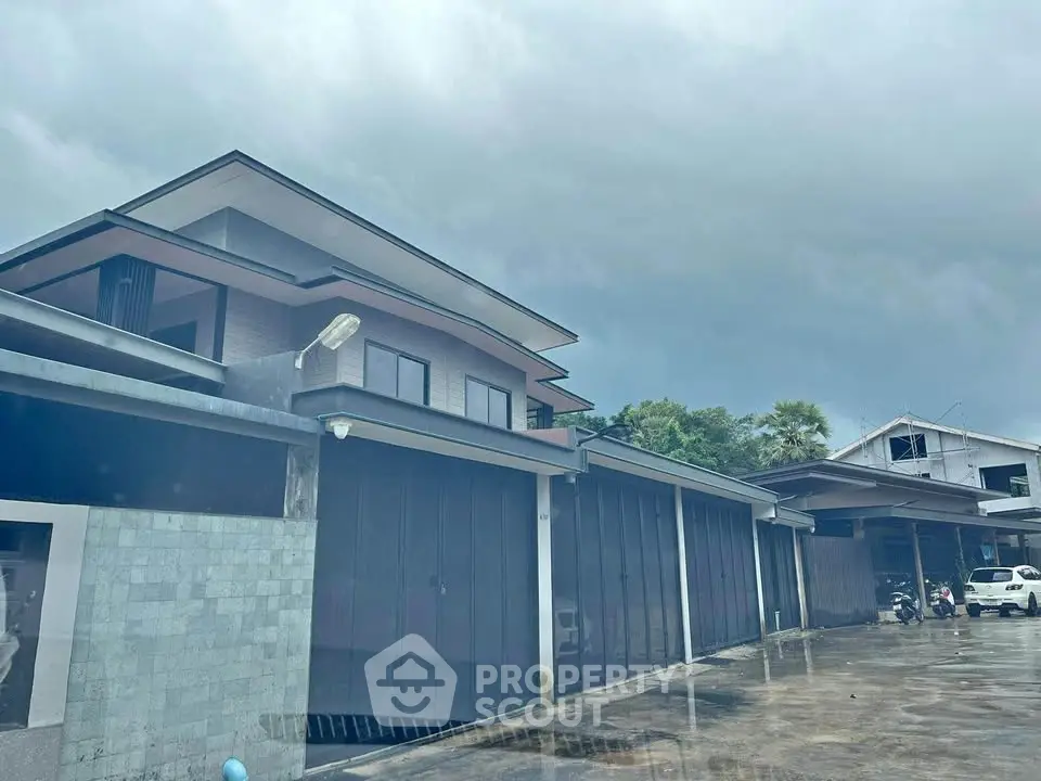 Modern multi-story building with sleek design and spacious garage area under cloudy sky.