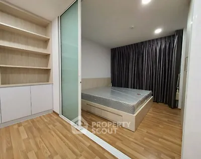 Modern bedroom with wooden flooring and built-in shelves, featuring a sliding glass door.