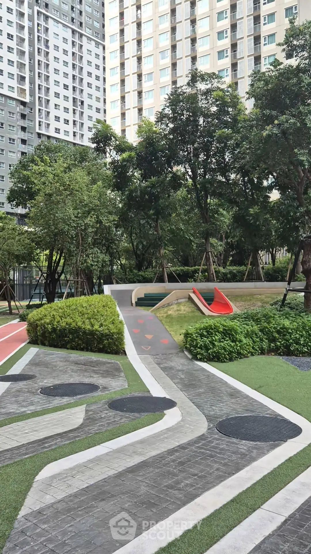 Modern residential complex with lush garden and playground area, perfect for family living.