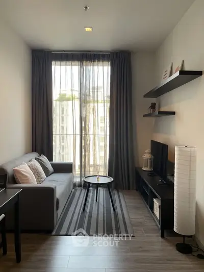 Modern living room with large window, stylish decor, and cozy seating area in urban apartment.