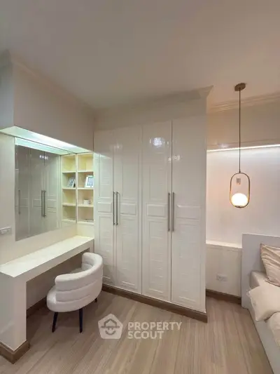 Elegant bedroom with built-in wardrobe and cozy study nook, featuring modern lighting and stylish decor.