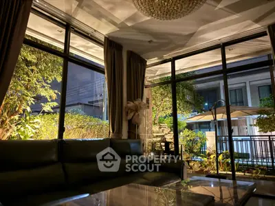 Luxurious living room with large windows and garden view at night