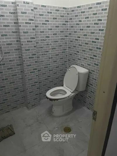 Modern bathroom with tiled walls and standard toilet in a real estate property.