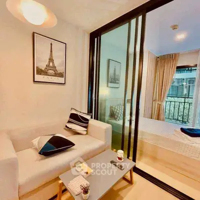 Cozy living room with sliding glass doors leading to a bright bedroom, featuring modern decor and natural light.
