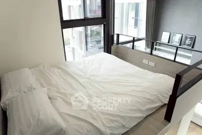 Modern loft-style bedroom with large windows and minimalist decor in urban apartment.