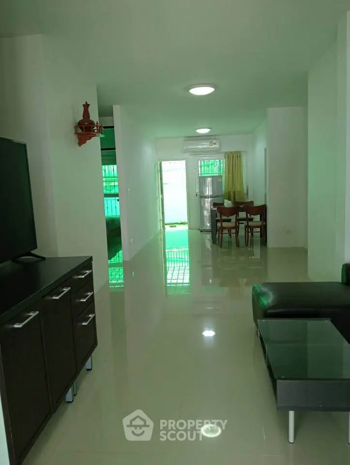 Spacious modern living room with sleek furniture and open layout leading to dining area.