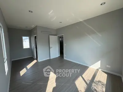 Spacious empty room with large windows and modern flooring, perfect for customization.