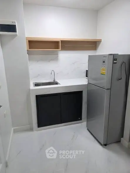 Modern compact kitchen with sleek fridge and minimalist design