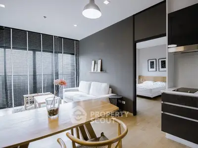 Modern open-plan living room with sleek kitchen and cozy bedroom in stylish apartment.