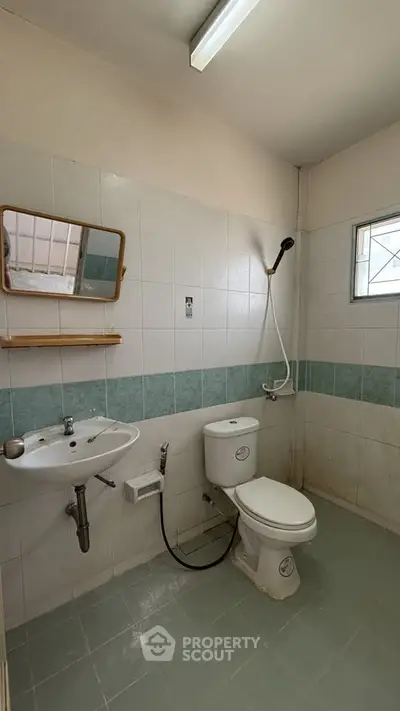 Compact bathroom with shower, sink, and toilet in a tiled setting.