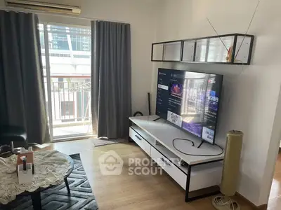 Modern living room with balcony access and stylish TV setup in urban apartment.