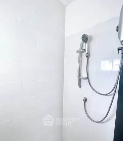 Modern bathroom shower with sleek white tiles and handheld showerhead
