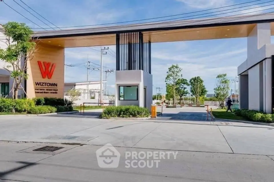 Modern entrance of a residential complex with sleek design and lush greenery.