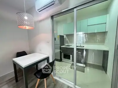 Modern kitchen with sleek design, featuring a glass sliding door, dining table, and air conditioning unit.