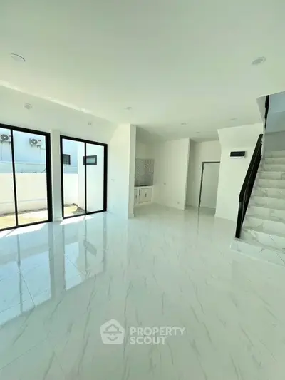 Spacious modern living room with large windows and sleek staircase