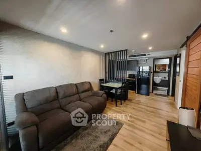 Modern living room with cozy sofa and dining area, featuring stylish wooden flooring and ambient lighting.