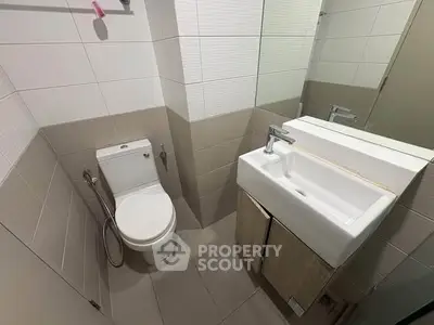 Modern bathroom with sleek fixtures and neutral tiles, featuring a compact design.