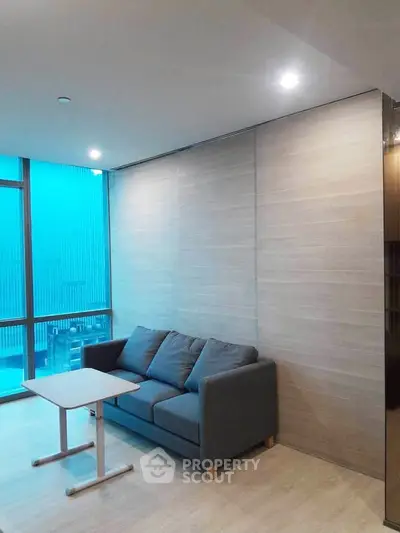 Modern living room with cozy sofa and sleek table, featuring floor-to-ceiling windows for natural light.
