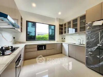 Modern kitchen with sleek cabinetry and large window offering garden view