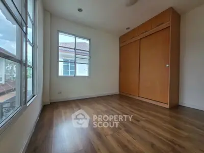 Spacious bedroom with wooden flooring and built-in closet, featuring large windows for natural light.