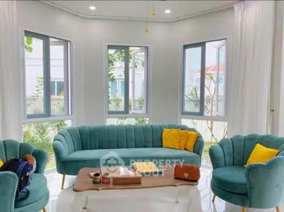 Chic and modern living room with stylish teal furniture and large windows offering natural light.
