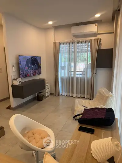 Modern living room with sleek design, featuring a wall-mounted TV and air conditioning, perfect for relaxation.