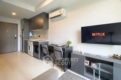 Modern living room with sleek kitchen, washing machine, and wall-mounted TV in stylish apartment.