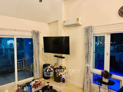 Spacious living room with modern decor, featuring a wall-mounted TV, air conditioning, and large windows for natural light.