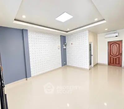 Spacious modern living room with sleek tile flooring and stylish accent wall, perfect for contemporary living.