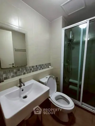 Modern bathroom with sleek sink, toilet, and glass shower enclosure in a stylish apartment.