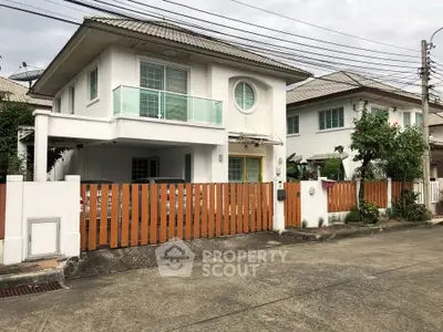 Charming two-story house with balcony and fenced yard in a suburban neighborhood.